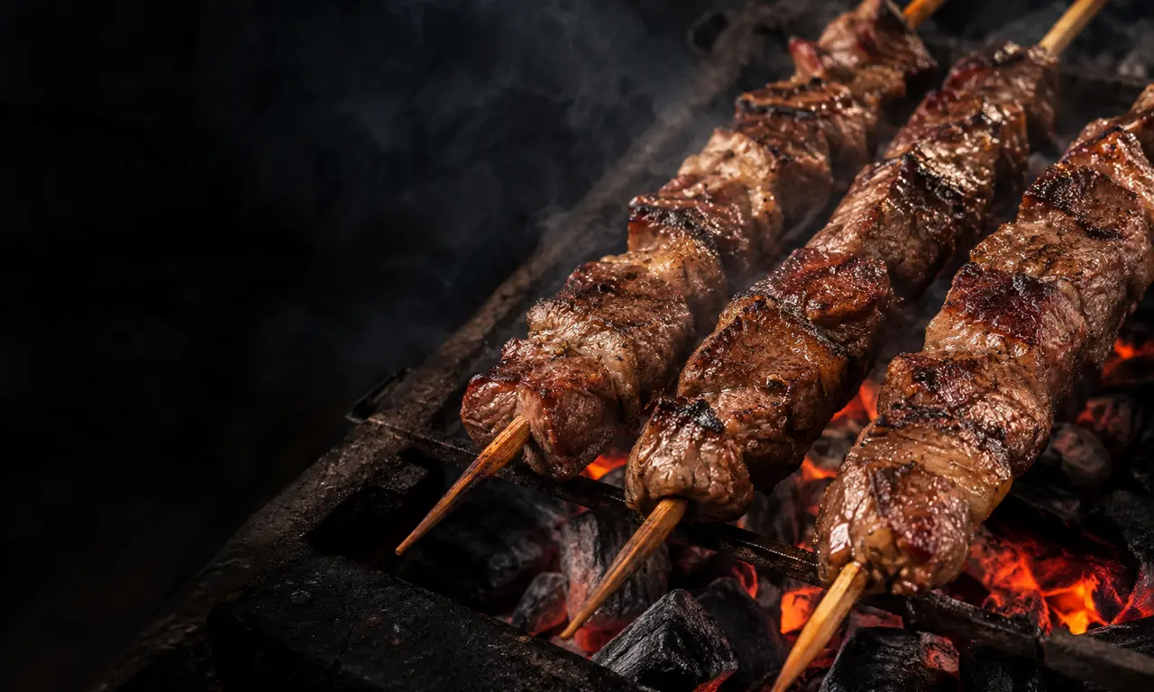 Espetinhos de carne dourando na brasa. Imagem ilustrativa.